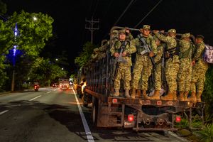 위장복을 입고 소총으로 무장한 군인들이 산 마르코스에서 트럭에 서 있습니다