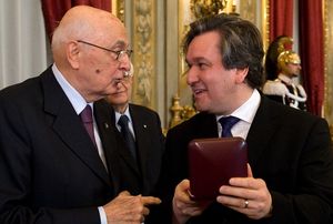 왼쪽에 있는 나이든 남자가 오른쪽에 있는 젊은 남자에게 상을 주는 사진