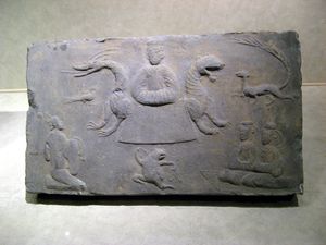 서왕모는 호랑이와 용의 호위를 받으며 옥좌에 앉아있다. 그녀는 구미호, 두 명의 여성, 뛰는 개구리, 남성 시종, 그리고 삼족오로 둘러싸여 있다. (동한 왕조, 서기 25~220년)