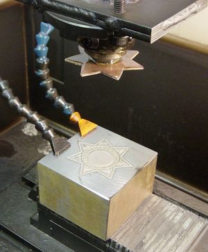 싱커 EDM. 전해질 용액이 공작물을 포화시키고 전압이 상단 싱커와 하단 공작물 사이에 가해진다.