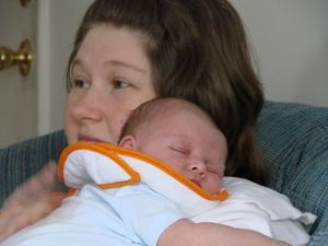 성인의 어깨에 기대어 트림하는 아기