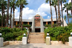 상단에 "쥬라기 공원", 하단에 "디스커버리 센터"가 적혀 있고, 그 사이에 티라노사우루스 골격이 있는 바위 패널이 있는 시설의 입구.