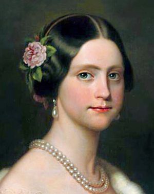 한쪽 어깨에 에르민 외투를 걸치고, 목에 큰 진주 목걸이 두 줄을 하고, 진주 귀걸이를 하고, 오른쪽 귀 위에 핑크색 동백꽃을 꽂은 젊은 여성의 초상화