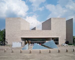 National Gallery East Building의 외관, 회색의 큰 건물, 돌로 된 광장 위에 솟아 있습니다. 건물 양쪽에 짧고 사각형의 탑이 있고, 광장 중앙에는 불규칙한 유리 피라미드가 배열되어 있습니다.