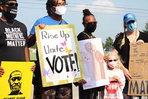 6월 9일, 텍사스주 피어랜드에서 열린 플로이드의 장례 행렬 경로를 따라, 코로나19 마스크를 쓰고 표지판을 든 채 장례 행렬에 참여한 시위대