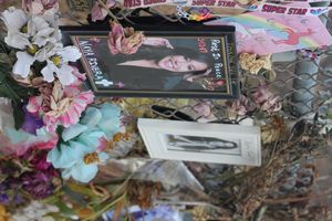 금속 울타리에 붙어 있는 사진, 꽃, 카드.