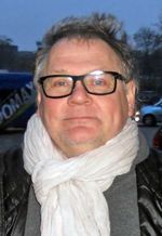 2014년 흰색 스카프와 검은색 조끼를 입은 야누스 카민스키 사진.