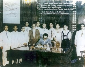 마닐라 대통령궁에서 마누엘 케손 대통령이 삼보앙가시 헌장에 서명하는 공식 행사, 법안 저자 후안 S. 알라노 의원과 부인 라모나, 삼보앙가 시장 파블로 로렌조, 젊은 마. 클라라 로렌조(로브레갓)가 교복을 입고 참석.