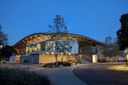 황혼에 밝게 빛나는 물결 모양 지붕으로 통합된 모듈로 구성된 현대적인 회색 건물인 스튜디오 미술관 전경