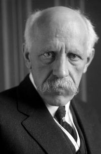 Nansen shown in later years with white, receding hair; characteristic drooping white mustache; and intensely focused eyes.