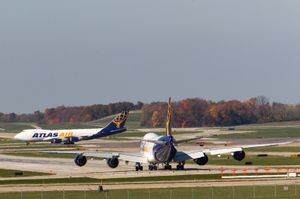 아틀라스 항공의 보잉 747-8F가 신시내티/노던켄터키 국제공항의 활주로 27번에서 대기하고 있으며, 항공사의 747-400F 중 하나가 활주로 18C에 착륙하고 있다.