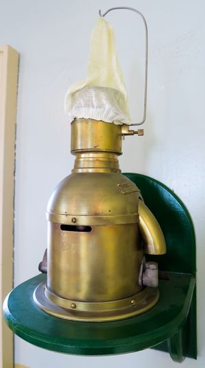 의 찬스 브라더스 백열 석유 증기 설치로, 1976년까지 섬버그 헤드(Sumburgh Head) 등대의 빛을 냈다. 이 램프(약 1914년 제작)는 기화된 등유(파라핀)를 태웠다. 기화기는 점화를 위해 변성 알코올(메틸화된 알코올) 버너로 가열되었다. 점화되면 기화된 연료의 일부가 분젠 버너로 전환되어 기화기를 따뜻하게 유지하고 연료를 증기 형태로 유지했다. 연료는 공기로 램프에 공급되었고, 등대지기는 매시간 공기 용기를 펌핑하여 파라핀 용기에 압력을 가해 연료를 램프로 밀어 넣었다. 사진 속 "흰 양말"은 증기가 연소되는 미연소 맨틀이다.