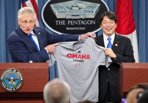 국방장관 척 헤이글이 2014년 7월 11일 미국 국방부에서 열린 공동 기자회견에서 오노데라 이쓰노리 일본 방위대신에게 네브래스카 오마하 대학교 테니스 셔츠를 증정하고 있다.