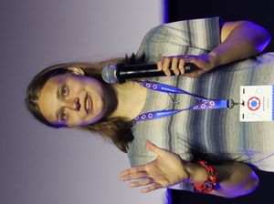 A woman with medium-length hair wearing a black shirt and smiling.
