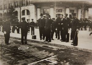 수류탄이 떨어진 곳을 표시하는 원 주위에 모인 경찰, 배경은 경시청 (1932)