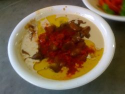 타히니와 올리브 오일을 곁들인 알레포 스타일의 풀, 알레포 고추 소스를 얹음