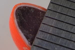 밀리미터 자와 함께 단면을 보여주는 주황색 M&M's. 설탕 패닝 코팅 층을 볼 수 있다.