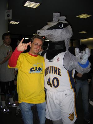 A person in a mascot costume dressed as Peter the Anteater performs the "Rip 'Em 'Eaters" hand signal (two middle fingers pinched with the thumb, with pinky and index finger sticking up as "ears") with a fan