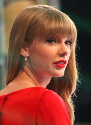 테일러 스위프트가 밴조를 연주하며 베이지색 블라우스와 양갈래 머리를 하고 라이브 공연을 하고 있다