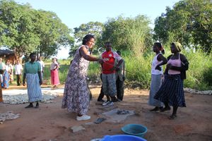 공동체 주도 위생 관리(CLTS)를 위한 동기부여 활동에서 마을 주민들이 파리가 사람의 대변과 음식을 왔다갔다하며 병을 옮기는 모습을 지켜보고 있다. (말라위호 근처 마을, 말라위)