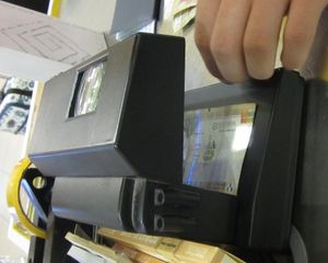 페루에서 사용 중인 지폐 검사 장치. 세부 검사를 위한 돋보기와 보안 띠를 보여준다.