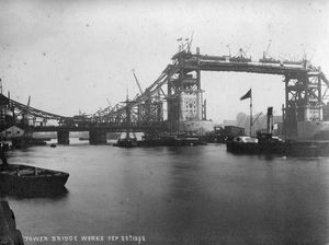 A black and white photograph of the Tower Bridge during its construction.
