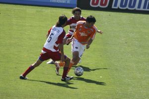 브라이언 칭이 두 명의 FC 댈러스 선수들을 제치고 드리블하고 있다.