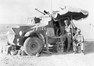 1940년 7월 26일, 리비아 국경에서 순찰 중 휴식을 취하면서 양산을 사용해 그늘을 만드는 제11 기병연대 장교들. 차량은 모리스 CS9 장갑차이다.