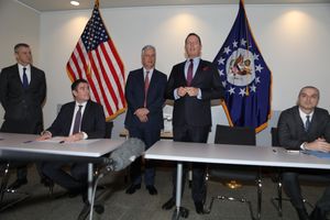 밀룬 트리부나크 세르비아 경제부 차관(왼쪽 앉은), 리처드 그레넬, 미국 대통령 특사 세르비아 및 코소보 평화 협상 (오른쪽 서 있는), 에세트 베리샤, 코소보 민간 항공청 청장 (오른쪽 앉은)