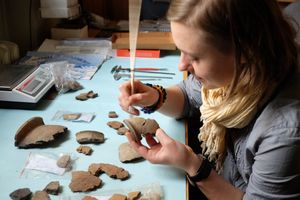 폴란드 Chodlik에서 출토된 초기 중세 시대 도기 조각을 세척하는 고고학자