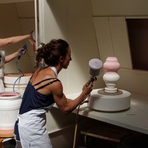 꽃병에 유약을 분사하고 있다.