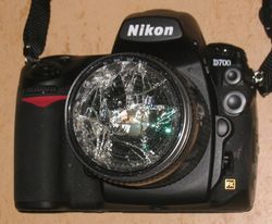 그 아래의 Nikkor 렌즈를 보호했을 수도 있는 파손된 필터가 장착된 Nikon D700. 일반적으로 예상할 수 있는 모든 것은 긁힘, 흠집 및 공기 중 오염 물질로부터의 보호이다.