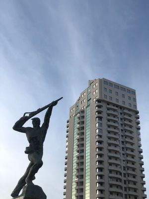 고층 건물을 배경으로 한, 정체불명의 병사를 묘사한 사회주의 현실주의 조각상