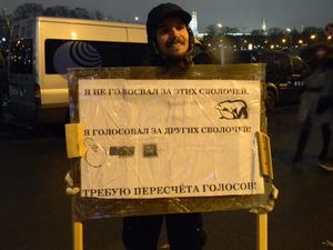 12월 10일 볼로트나 광장의 시위자. 표지판에는 "나는 이 녀석들(통합 러시아 조롱 로고)에게 투표하지 않았고, 다른 녀석들(야블로코, 정의 러시아, 러시아 연방 공산당 로고)에게 투표했다. 투표 재검표를 원한다."라고 적혀 있다.