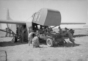 전면 조종석이 올라가고 지프차 4명이 안으로 밀어넣는 와코 글라이더