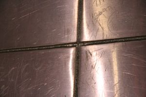 아치의 외피 용접은 4x8피트 스테인리스 스틸 시트 사이의 틈새를 밀봉한다. 낙서가 기념물의 아래 5~7피트 지점에 긁혀 있다.