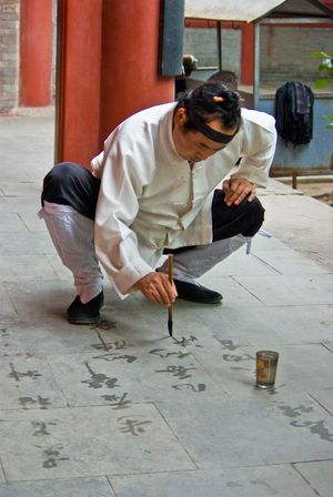돌 위에 물로 서예를 하는 도교 승려. 모래 만다라와 같이, 수서예는 물리적 현실의 덧없는 본성을 연상시킨다.