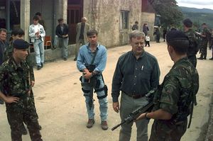 1996년 보스니아 헤르체고비나에서 경호원과 함께 있는 미국 국방부 차관보 월터 B. 슬로콤. 경호원은 M16 소총으로 무장하고 있다.