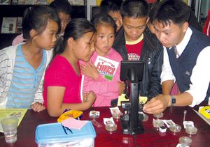 라오스의 비영리 프로젝트 Big Brother Mouse(en)가 주최하는 행사에서 어린이가 처음으로 현미경을 사용하는 모습. 교육과 문해력 향상을 목표로 한다.