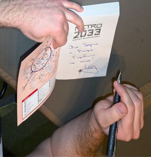 드미트리 글루홉스키가 2012년 SFeraKon에서 메트로 2033 책에 서명하고 있다.