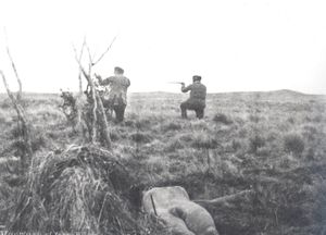 율리우스 포퍼(왼쪽)가 사격하는 모습, 배경에 셀크남족 시체가 보인다