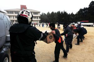 일본 시민들이 미 해군 헬리콥터에서 구호 물품을 내리기 위해 인간 사슬을 만들고 있다.