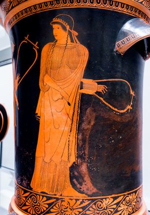 여자가 바르비토스를 들고 있는 적색 figure 화병 그림. 왼편에는 바르비토스를 든 수염 난 남자가 부분적으로 보인다.