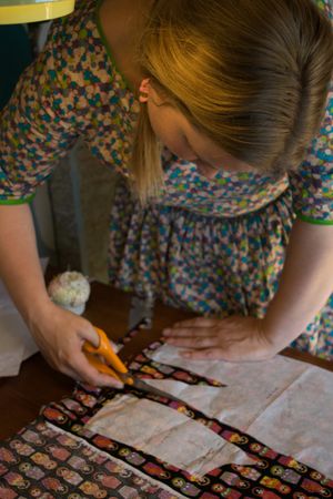 취미로 바느질하는 사람이 드레스를 만들기 위해 천을 자르고 있다.