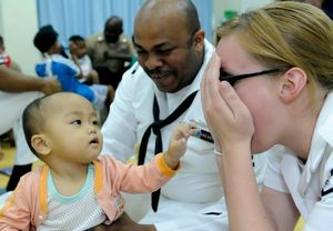 US Navy 100406-N-7478G-346 Operations Specialist 2nd Class Reginald Harlmon and Electronics Technician 3rd Class Maura Schulze play peek-a-boo with a child in the Children's Ward at Hospital Likas