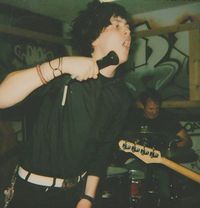 A vocalist and a drummer of a band performing with their band.