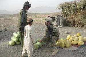 아프가니스탄 샤왈리코트 지역에서 한 군인이 현지 상인에게서 신선한 멜론을 구매하고 있다.