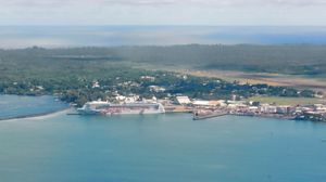 프라이드 오브 아메리카가 힐로 항에 정박해 있으며, 힐로 국제공항 활주로가 배경에 보인다.