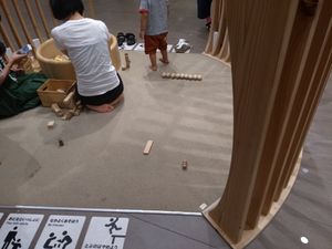 공공 놀이터에서 놀고 있는 여성과 아들. 입구에 신발이 놓여 있다.