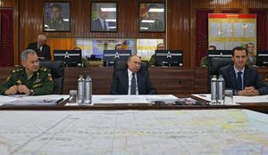  블라디미르 푸틴 (중앙), 바샤르 알 아사드 (오른쪽) 및 러시아 국방부 장관 세르게이 쇼이구 (왼쪽)와 함께 앉아 시리아 주재 러시아군 지휘소를 방문하여 군사 보고를 듣고 있다.